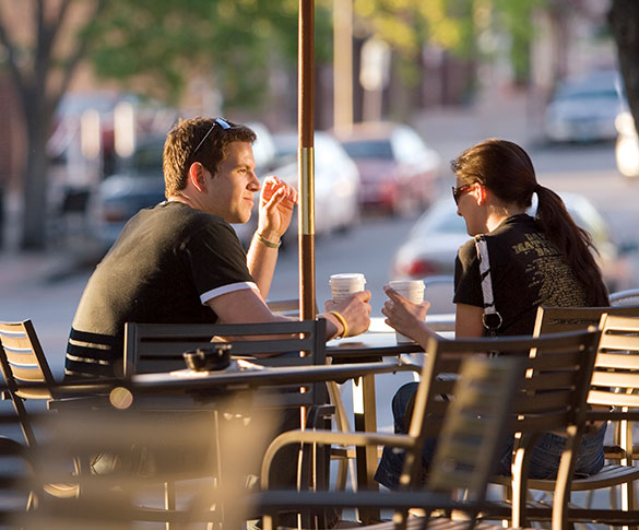Man and woman drinking coffee at cafe table on downtown sidewalk